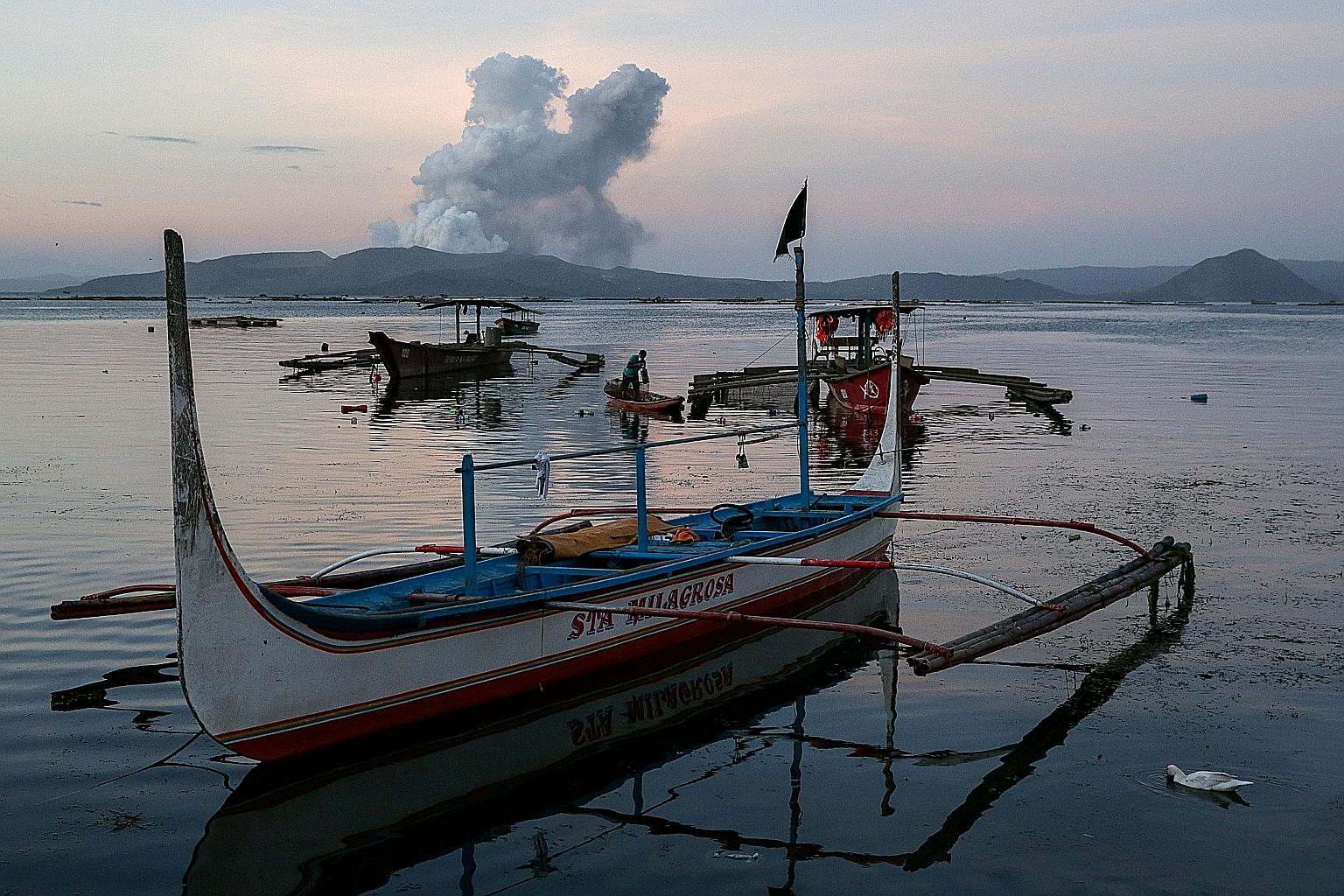 A fisherman at work as the Taal volcano in the Philippine province of Batangas shuddered continuously with quakes yesterday. Officials have warned people against speculating that the five-day eruption is waning.