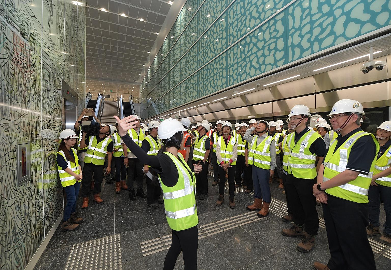 Ms Eileen Goh, assistant manager of Art In Transit at the Land Transport Authority, briefing visitors, including Transport Minister Khaw Boon Wan (third from right), on the significance of the artwork Tree Of Memories by artist Koh Hong Teng at Sprin