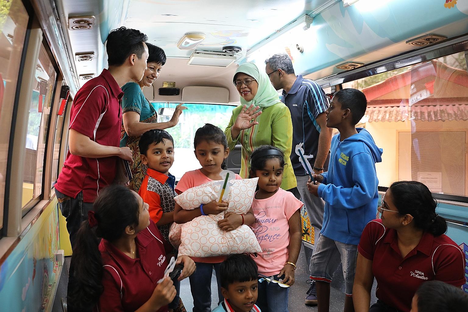 President Halimah Yacob and Sinda president Indranee Rajah (in green), Minister in the Prime Minister's Office and Second Minister for Finance and Education, touring the Sinda bus, which has been retrofitted to serve as a hub for activities like read