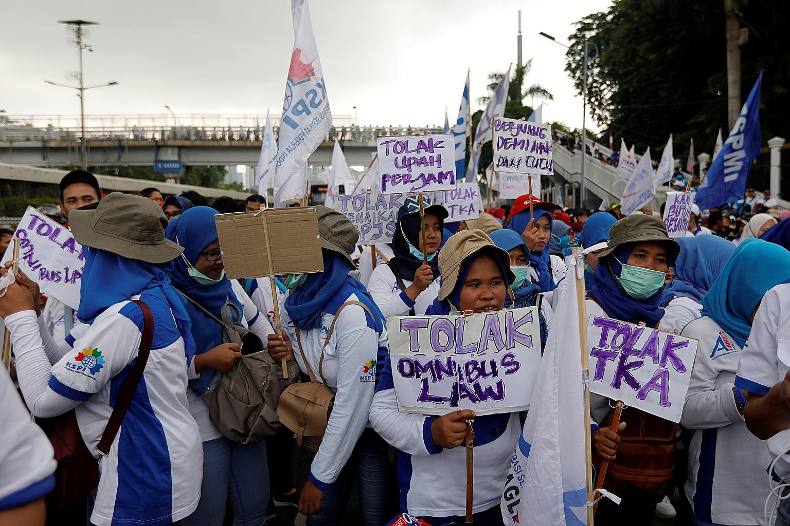 Labourers carrying placards which say "Against omnibus law and foreign workers" during a protest outside Parliament building in the Indonesian capital Jakarta yesterday. According to a union leader, the reforms could increase the risk of mass firings