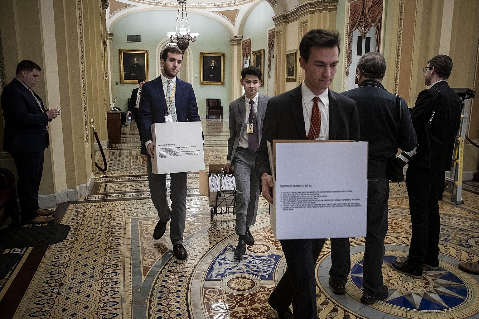 Staff carrying boxes of binders to the office of Senate Minority Leader Chuck Schumer at the US Capitol in Washington yesterday, ahead of the impeachment trial of President Donald Trump. The trial is expected to continue six days a week, Monday to Sa
