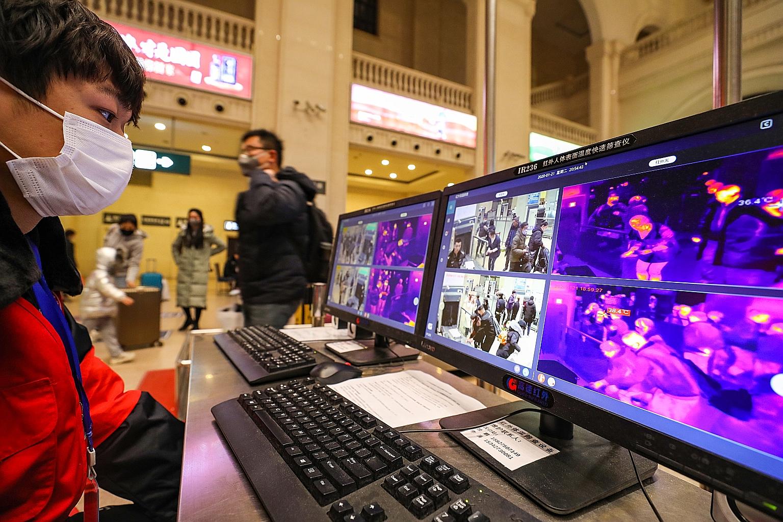 A worker monitoring infrared detectors for signs of fever among passengers at the Hankou Railway Station in Wuhan, China. Singapore also has temperature screening for all travellers arriving from China at Changi Airport.