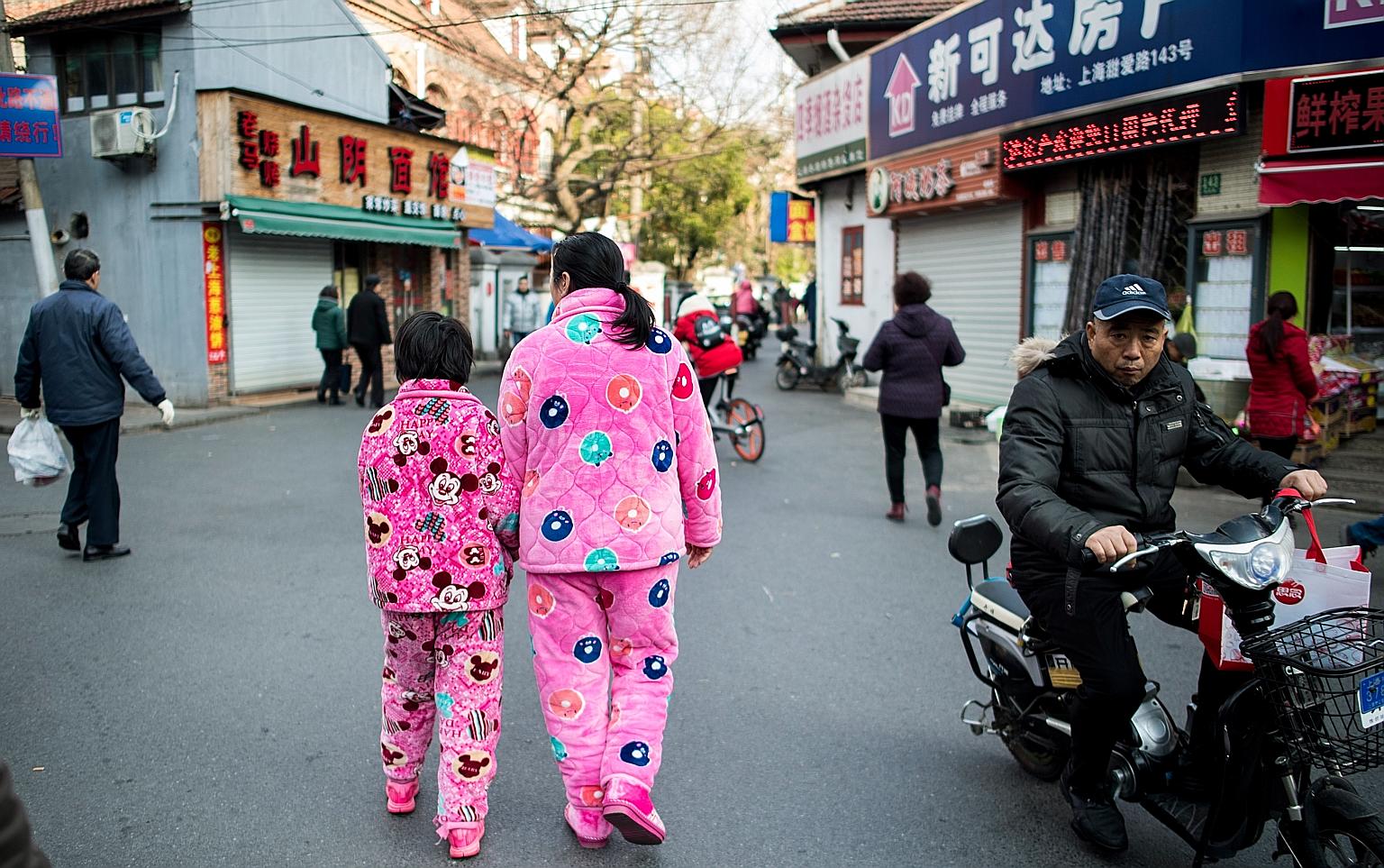 Wearing pyjamas outdoors is common in China, as seen in this photo of a woman and a girl in a street in Shanghai yesterday. The Chinese authorities have tried to stamp out the practice, but Suzhou city officials sparked outrage online when they used 
