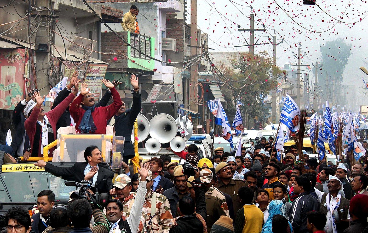 Aam Aadmi Party (AAP) leader and Delhi Chief Minister Arvind Kejriwal (in red sweater and blue scarf) greeting supporters during a roadshow on Wednesday in New Delhi for the upcoming elections. The polls will pit the Bharatiya Janata Party against th