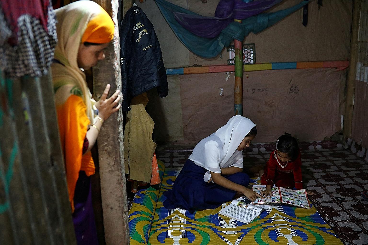 Yasmin, a Rohingya girl, helping her younger sister to study in the Leda refugee camp in Teknaf, Bangladesh, in this file photo from March 5 last year. Officials say Dhaka's move will provide schooling for Rohingya children till the age of 14 and tra