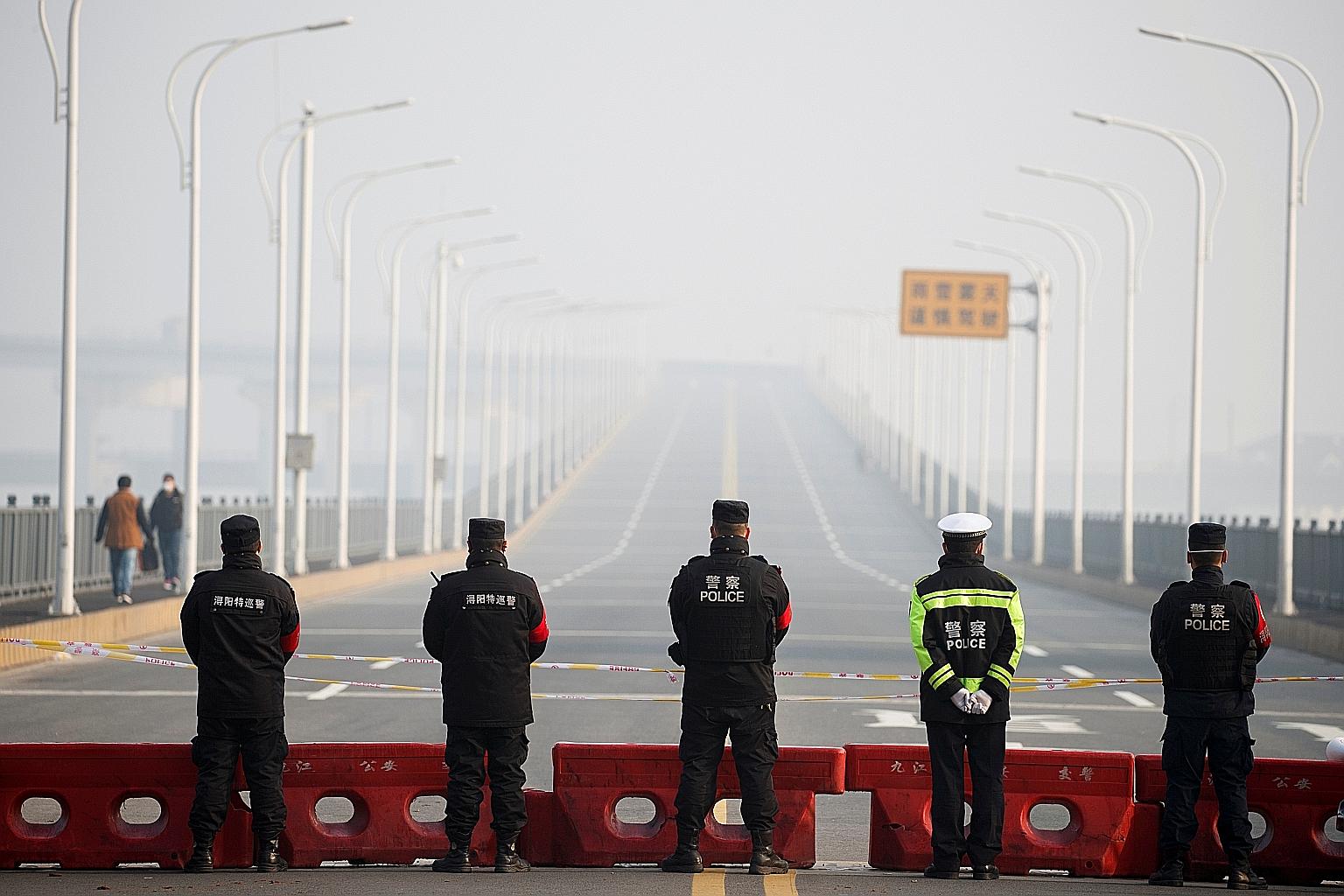 Police standing guard yesterday at a checkpoint at the Jiujiang Yangtze River Bridge that links Hubei province with Jiangxi province in China. The police said people were still entering Hubei and they could still get out, but only in "special circums