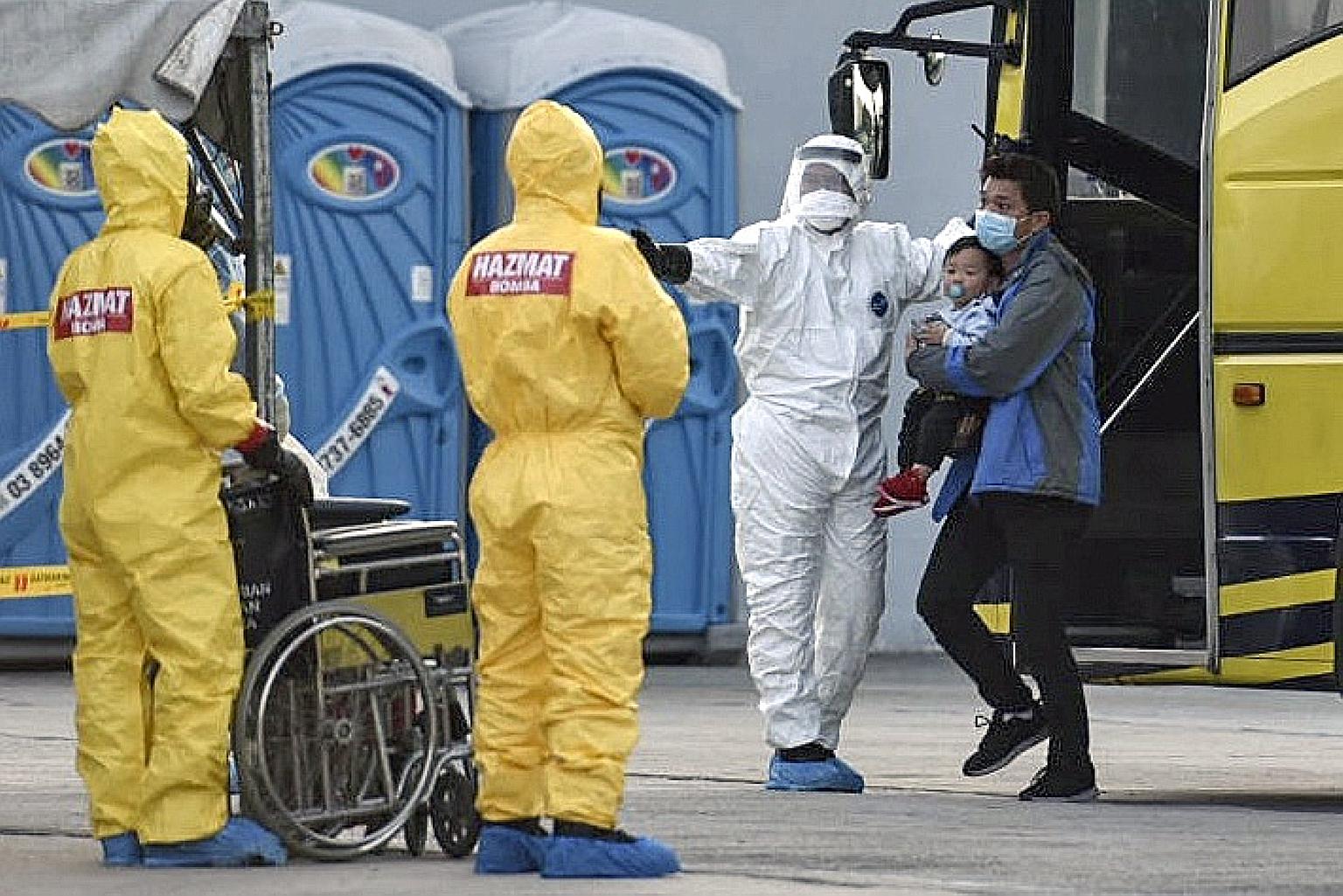 Two Malaysian nationals who were evacuated from China's Hubei province being directed from a bus by health officials after arriving at the Kuala Lumpur International Airport. PHOTO: EPA-EFE