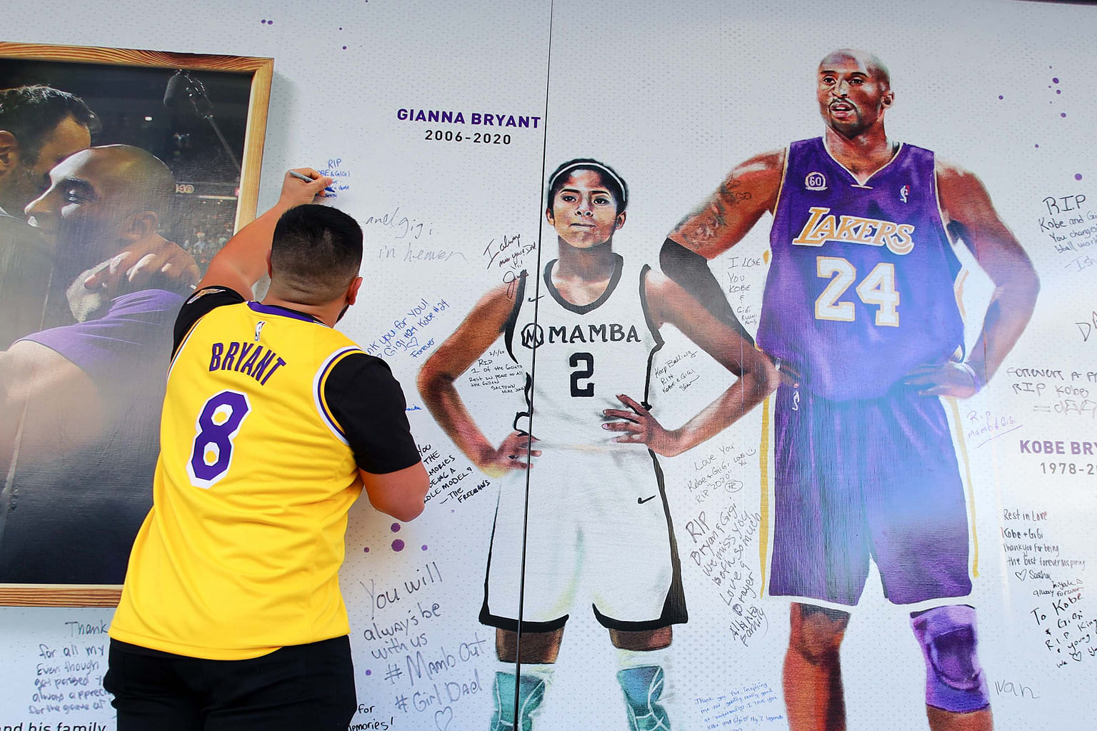 A fan writing a message on a wall in remembrance of Kobe and Gianna Bryant at Golden 1 Centre before the Lakers played the Kings. PHOTO: REUTERS