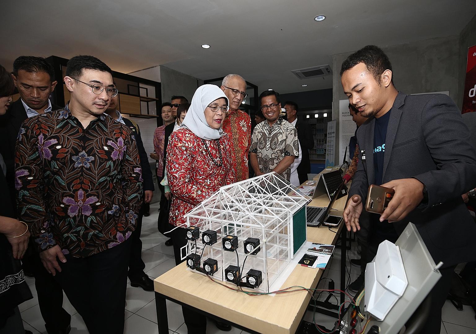 President Halimah Yacob, flanked by her husband Mohamed Abdullah Alhabshee and Salim Group executive director Axton Salim (left), on a tour of BLOCK71 Yogyakarta, a hub for budding entrepreneurs. Here, Kandang chief executive Ishaq Firdaus (right) is