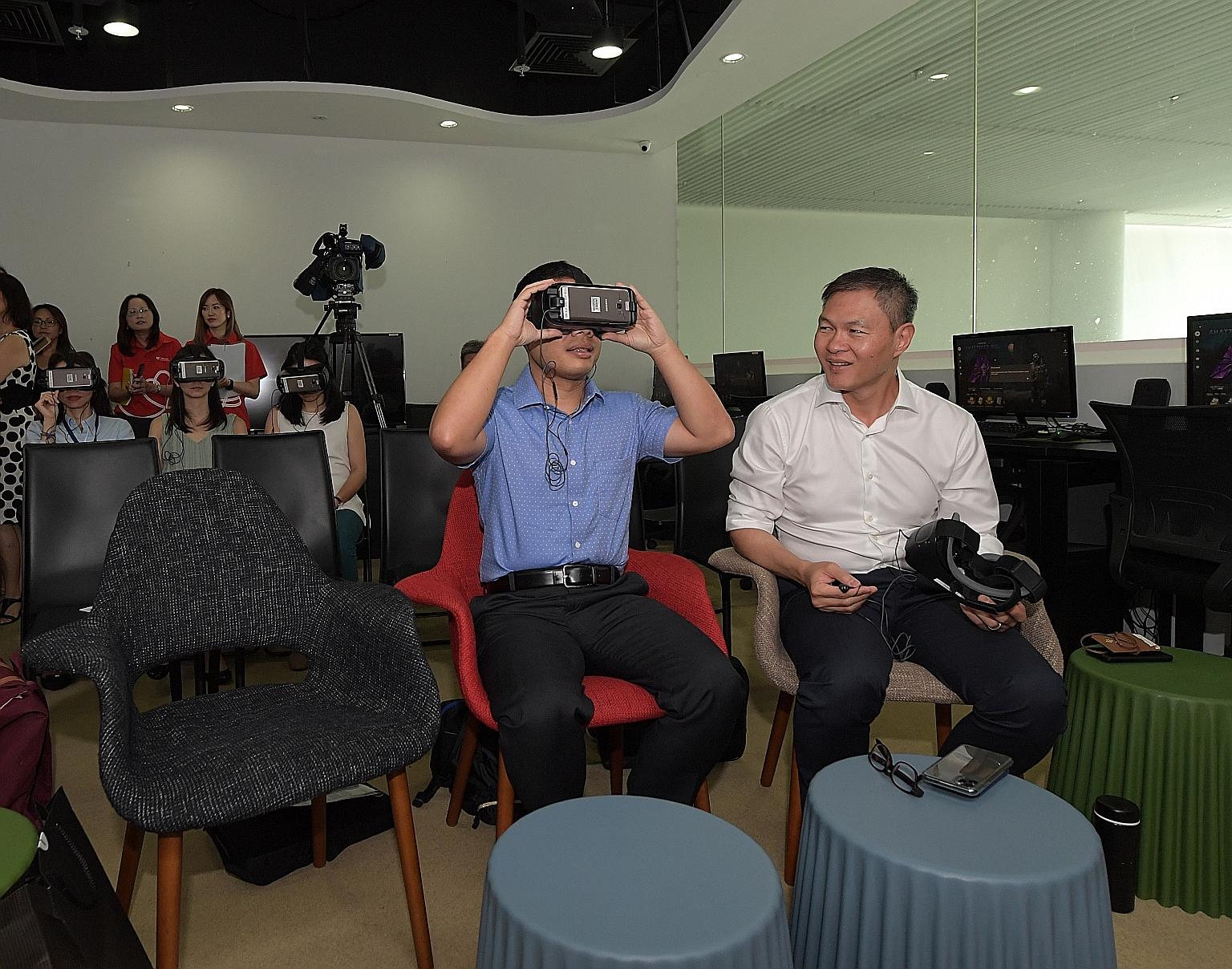 Minister for Social and Family Development Desmond Lee (centre) and Touch Community Services chief executive James Tan trying on virtual reality headsets at Touch Community Services at Leisure Park Kallang yesterday. Mr Lee tried out the Virtual Real
