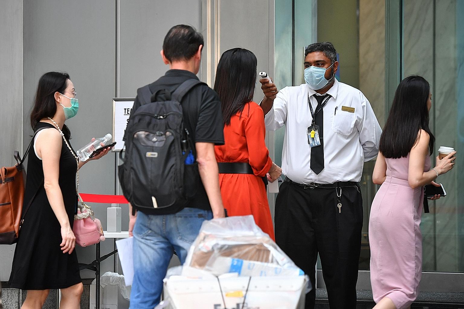 People queueing to get their temperatures taken at One Raffles Place yesterday. Snaking queues were seen at places like Raffles Place and Suntec City as temperature checks and visitor screening were carried out.