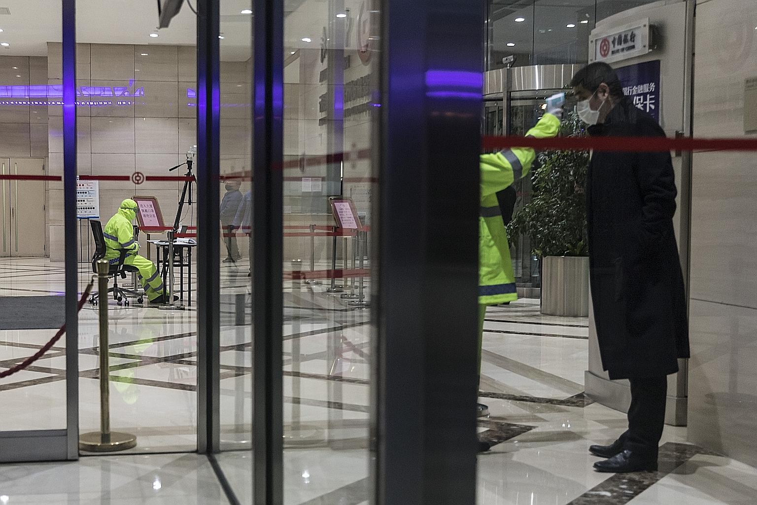 A man having his temperature taken at the Bank of China Tower in Shanghai on Monday. Bankers say preparations for potential Chinese initial public offerings are slowing, as efforts to limit the spread of the coronavirus have put key meetings on hold.