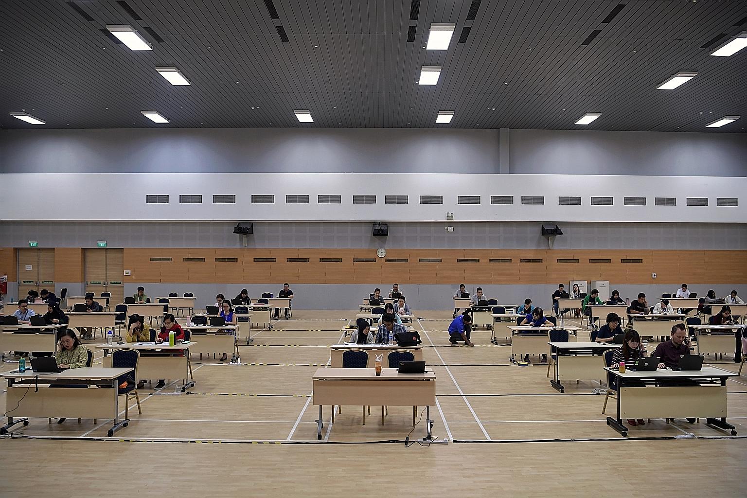Officers checking on work pass holders and conducting video calls with them at the LOA compliance call centre in the Ministry Of Manpower Services Centre yesterday.