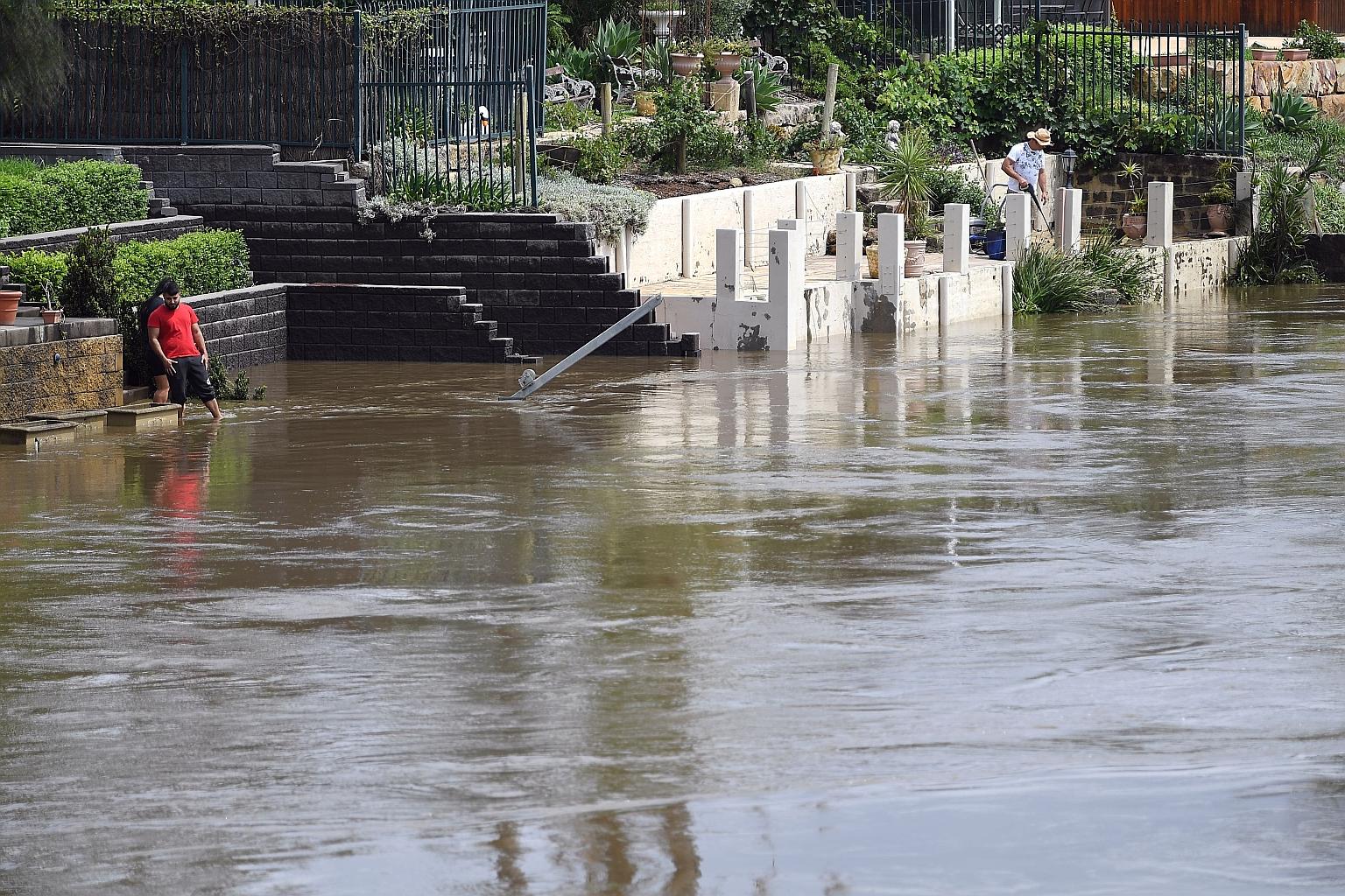 Residents on the banks of the swollen Georges River in Sydney waiting for water to recede on Monday. Yesterday, Nepean Dam south of Sydney was at full capacity and spilling over, with video footage showing excess water cascading over the dam wall and
