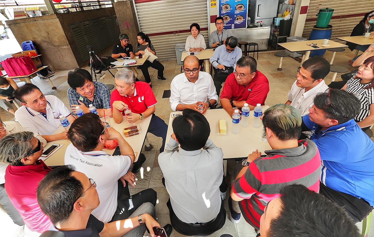 Senior Minister of State for Transport Janil Puthucheary (centre), with Mr Ang Hin Kee (third from left), adviser to the National Taxi Association and National Private Hire Vehicles Association, speaking to drivers yesterday about the relief package,