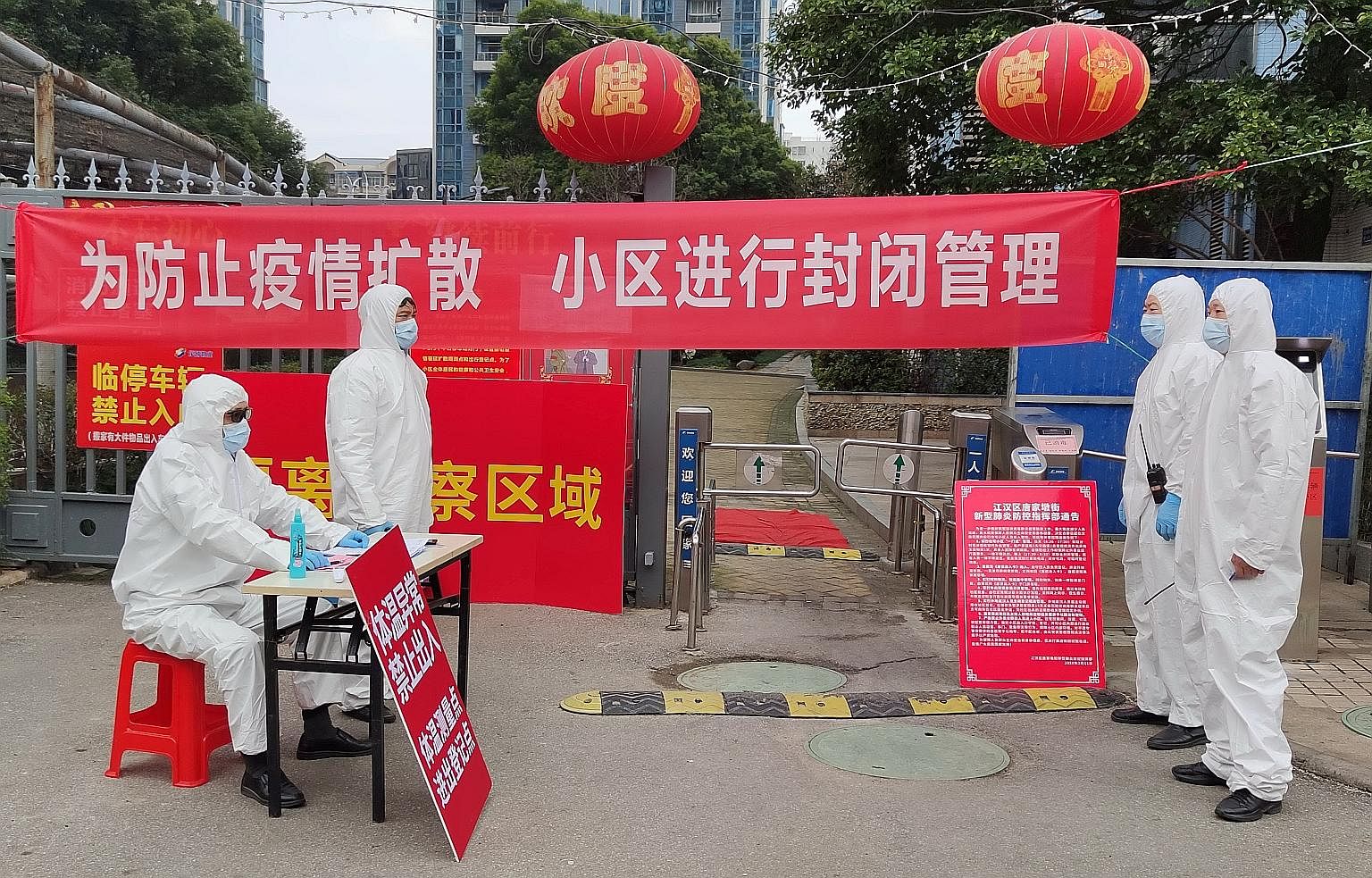 Workers manning a checkpoint where visitors have to register and get their temperature taken at an entrance to a residential compound in Wuhan, Hubei province, on Thursday.