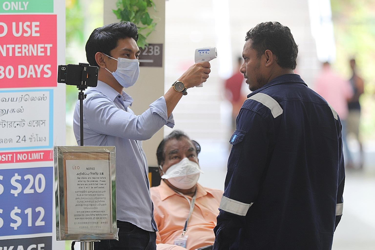 Far left: The Avenue South Residence project is facing construction delays because of a disruption in the deliveries of supplies from China, where factory openings are deferred. Left: A man getting his temperature taken at The Leo dormitory in Kaki B
