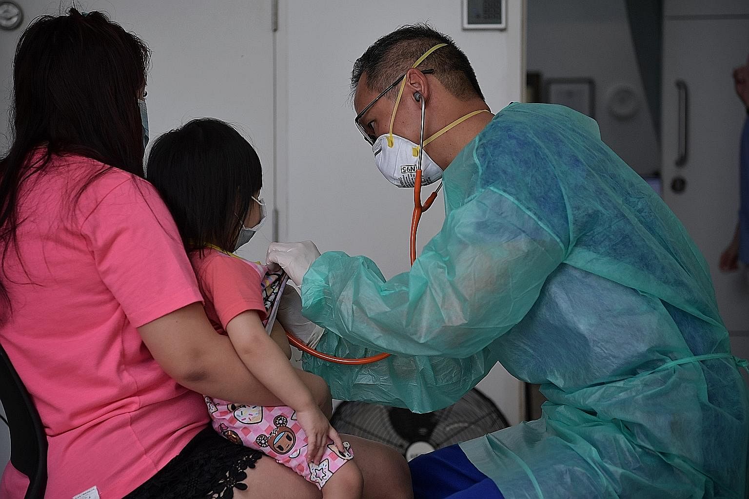 Dr Dale Lim checking a child patient with suspected flu symptoms at his clinic on Thursday. Besides assuring his patients, he has also assured his family that protection measures are in place.