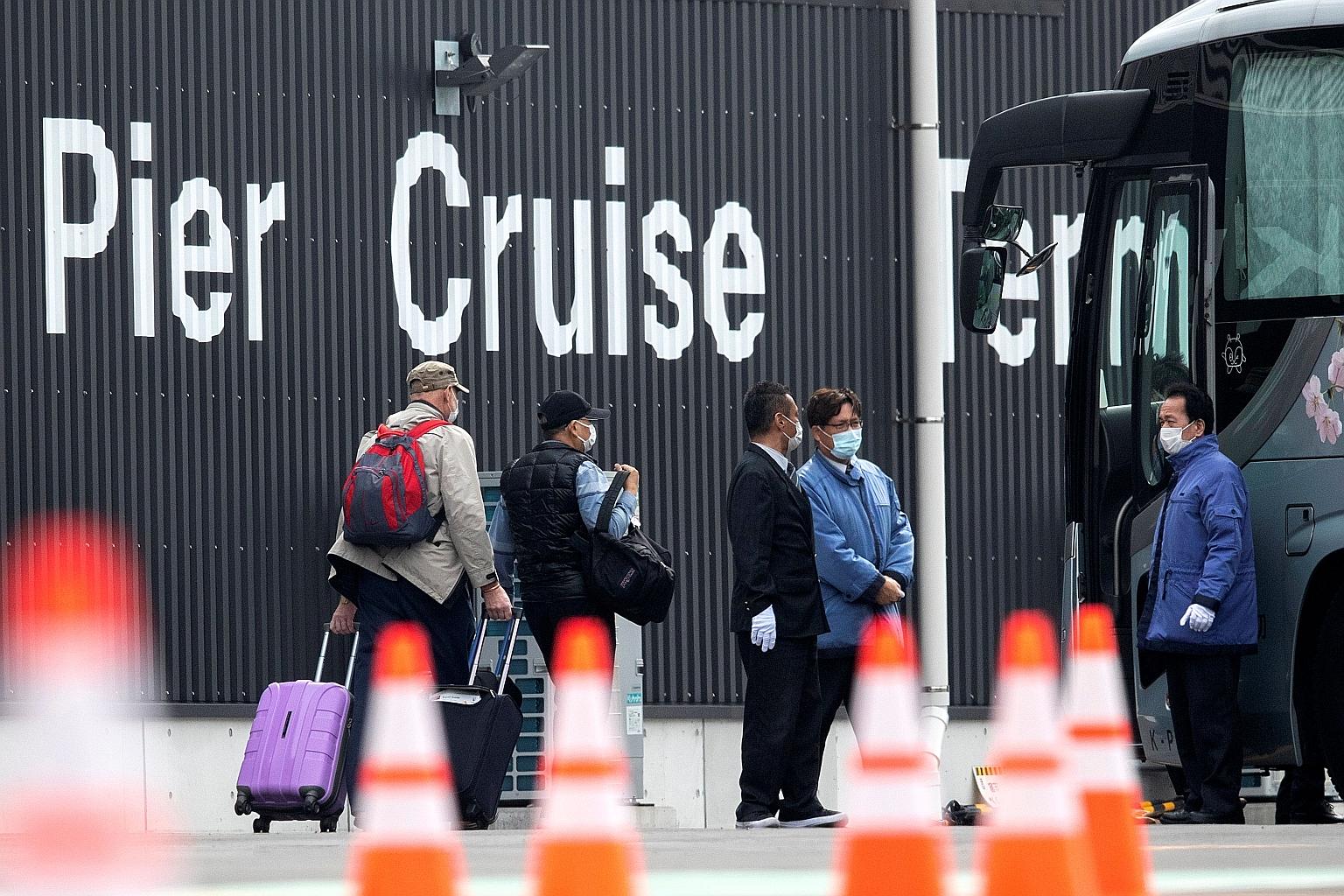 Two passengers wearing masks leaving the coronavirus-hit Diamond Princess at Daikoku Pier Cruise Terminal in Yokohama yesterday.