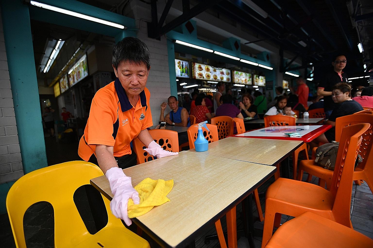 Madam Ho Siew Lan, 55, wearing gloves and using disinfectant and cloth to clean a table at GHK @ Khatib coffee shop in Yishun yesterday. The coffee shop has been held up as a model by the Public Hygiene Council, which yesterday launched a new initiat
