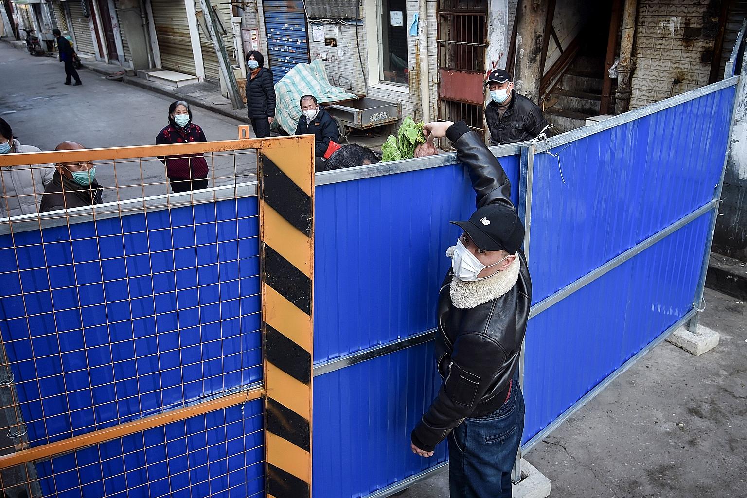 A man delivering vegetables to a person across the barrier preventing entry into Wuhan in China's Hubei province on Sunday.