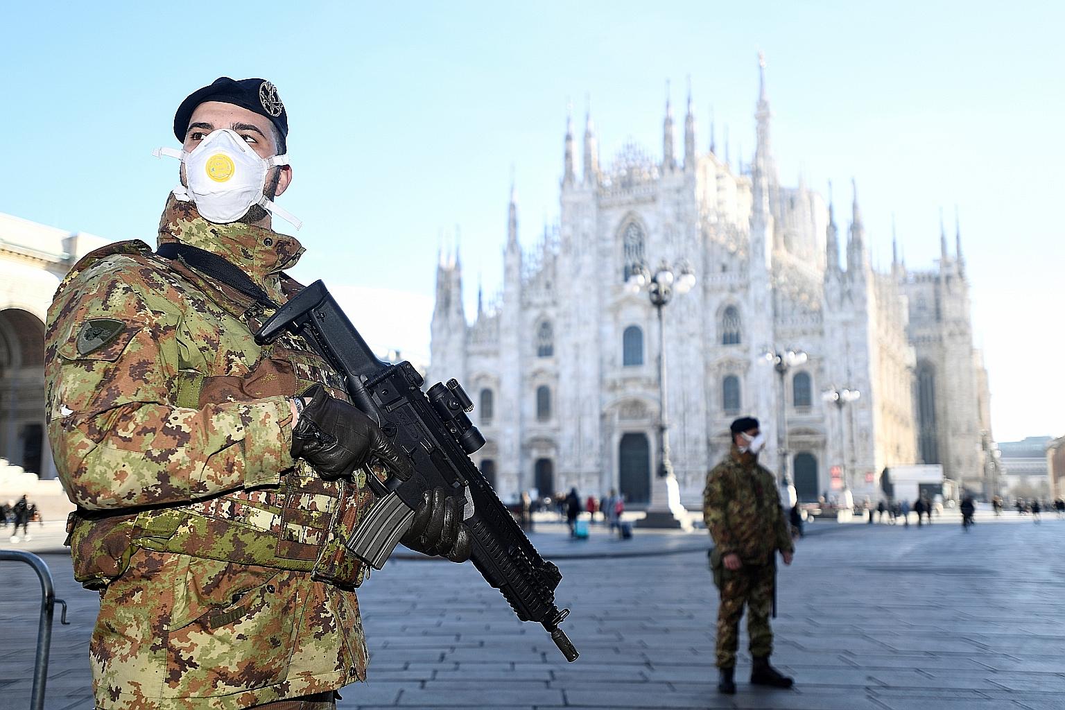 Military officers standing guard yesterday outside Milan's Duomo cathedral, which has been closed by the authorities due to the coronavirus outbreak. As Italy struggles to contain the virus, other countries are considering new measures to keep the vi