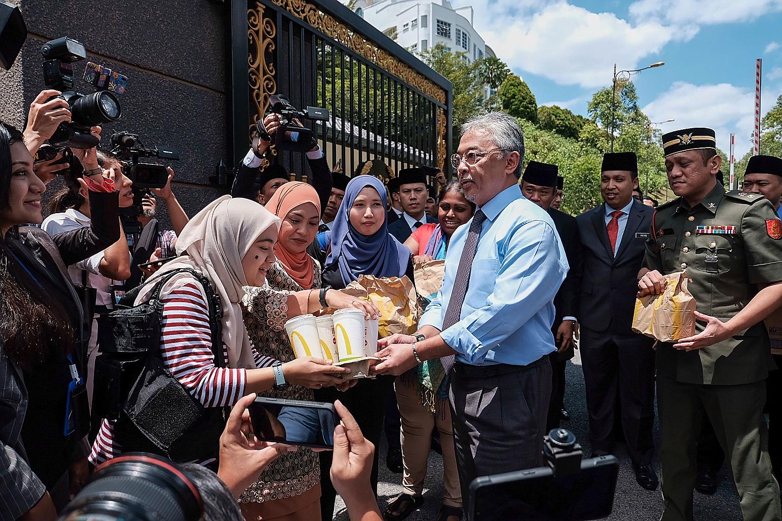 Malaysia's King, Sultan Abdullah Ri'ayatuddin, handing out McDonald's lunches to journalists waiting outside the Istana Negara in Kuala Lumpur yesterday. The country's titular head is an unprecedented central figure in the Malaysian political drama u