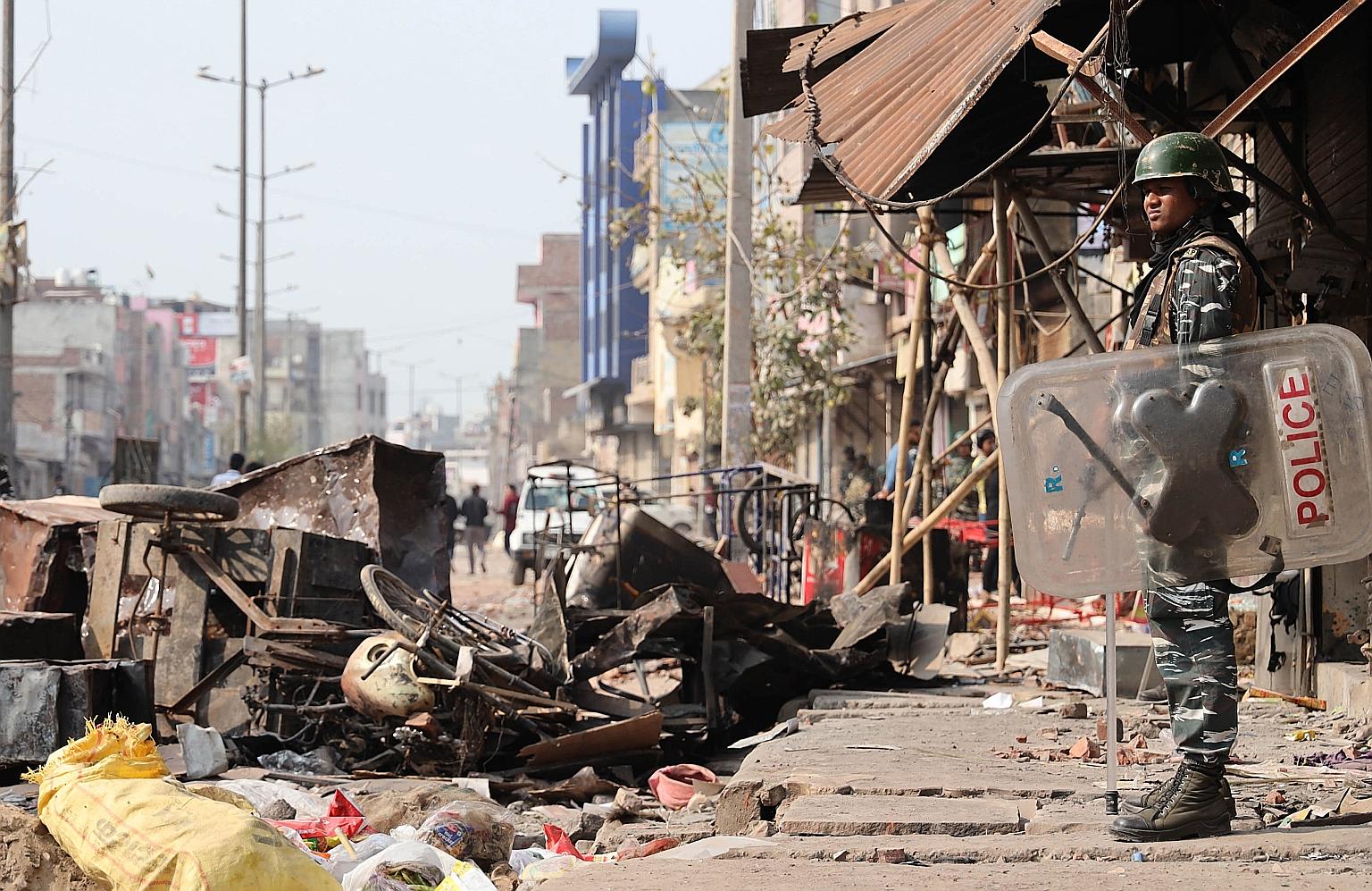 An Indian riot police officer standing guard at an area that was affected by deadly clashes in New Delhi yesterday. More than three dozen were killed and over 200 injured in fighting that broke out between supporters and opponents of the controversia