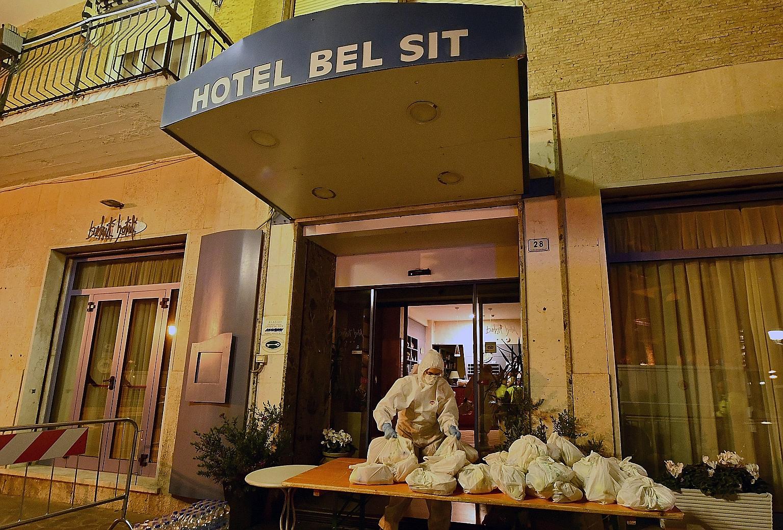 A civil protection and health worker in a protective suit and mask delivering the evening meal at the Hotel Bel Sit in Alassio, northern Italy, where 34 people are being quarantined.