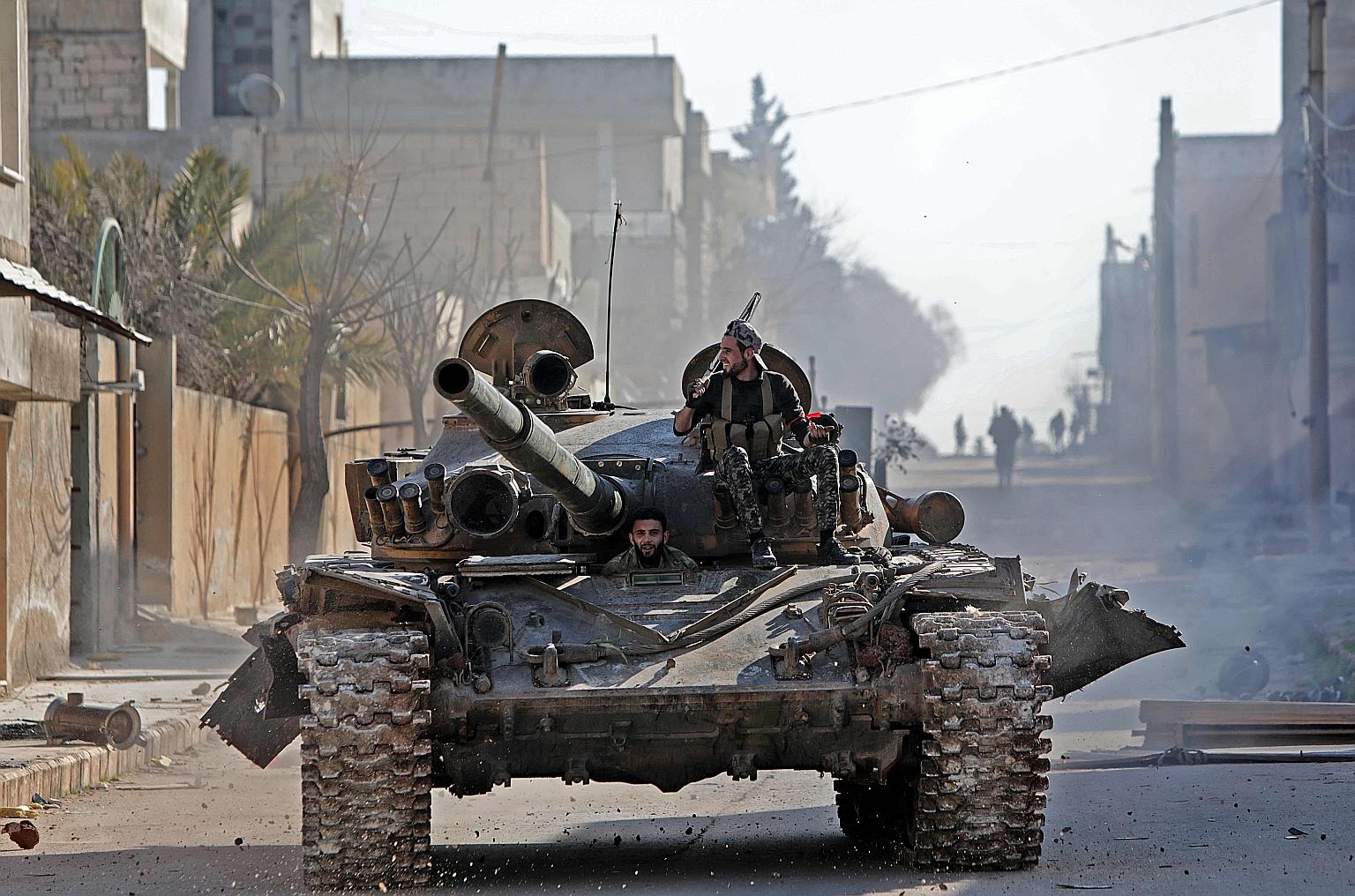 Turkey-backed Syrian fighters riding in a tank on Thursday in the town of Saraqib, in the eastern part of Syria's Idlib province.