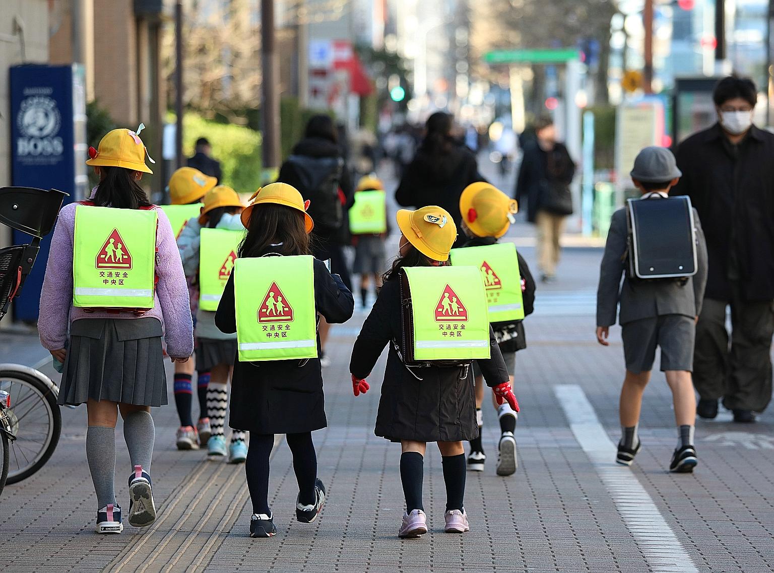 Children walking to school in Tokyo yesterday. Hokkaido schools have been shut since Thursday, while Tokyo, Osaka and Nagoya plan to close schools from Monday.