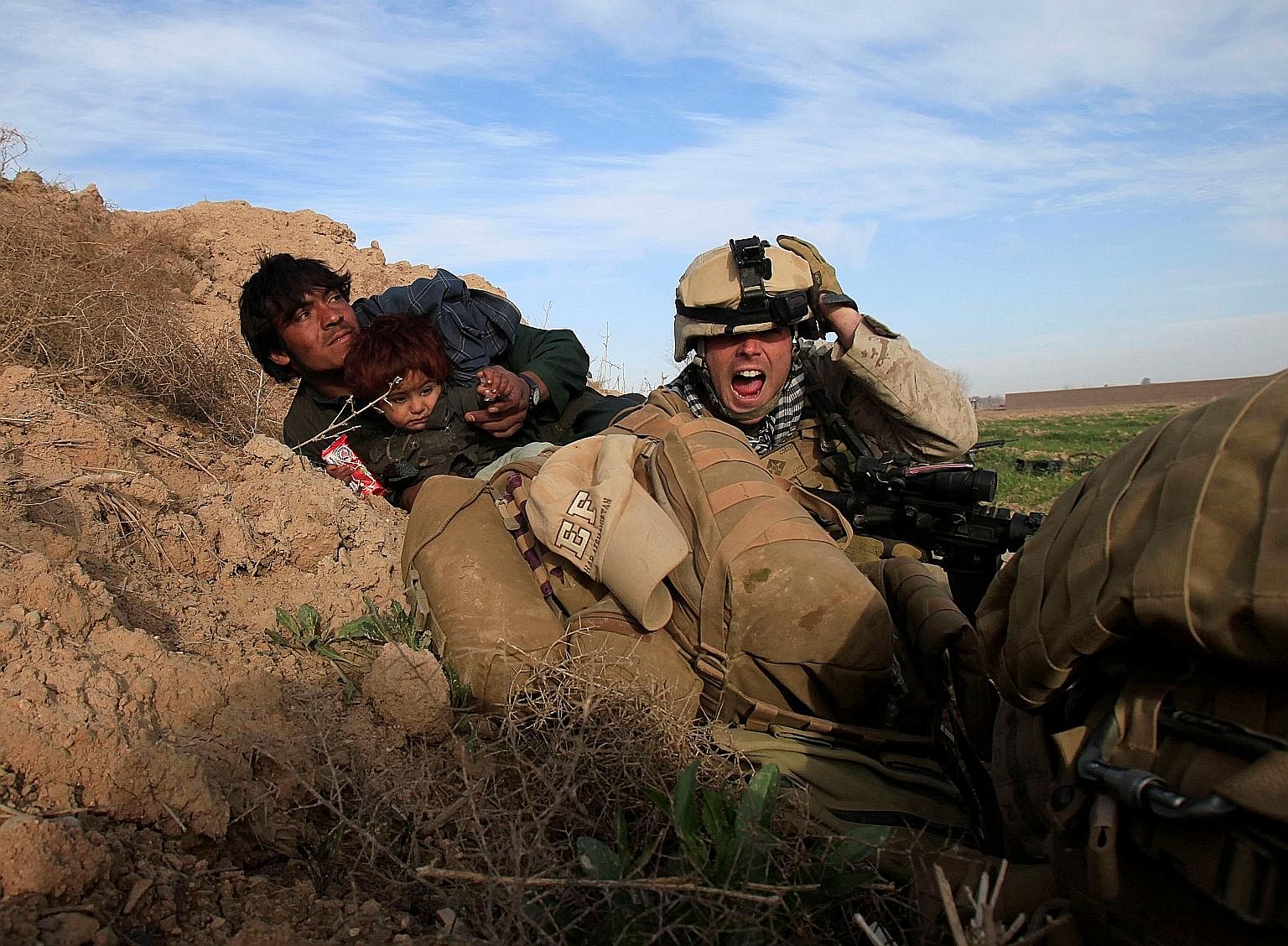 In this photo taken in 2010, a US Marine protects an Afghan man and his child after Taleban fighters opened fire in the Afghan town of Marjah.