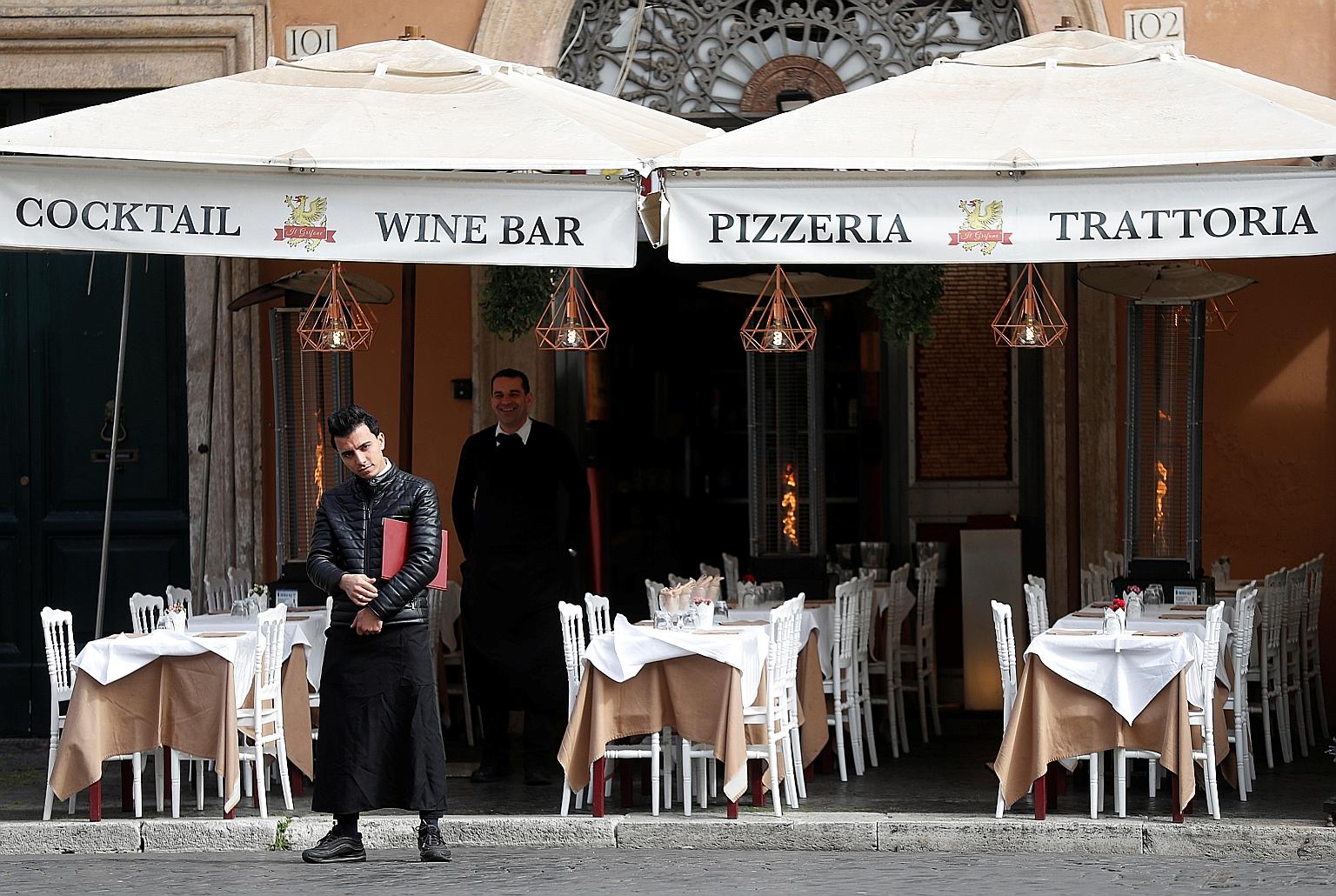 Staff at an empty restaurant in Rome yesterday after the government closed schools and cinemas, and urged people to work from home and not stand closer than 1m to one another.