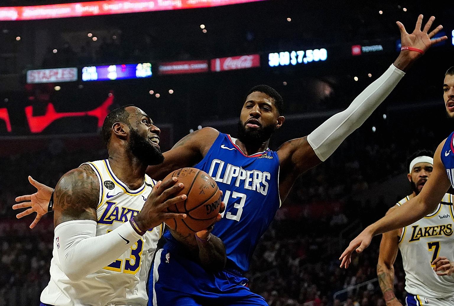 Lakers forward LeBron James taking on Clippers guard Paul George in the NBA game at Staples Centre on Sunday. He scored 28 points while Anthony Davis had a team-high 30 points. PHOTO: REUTERS