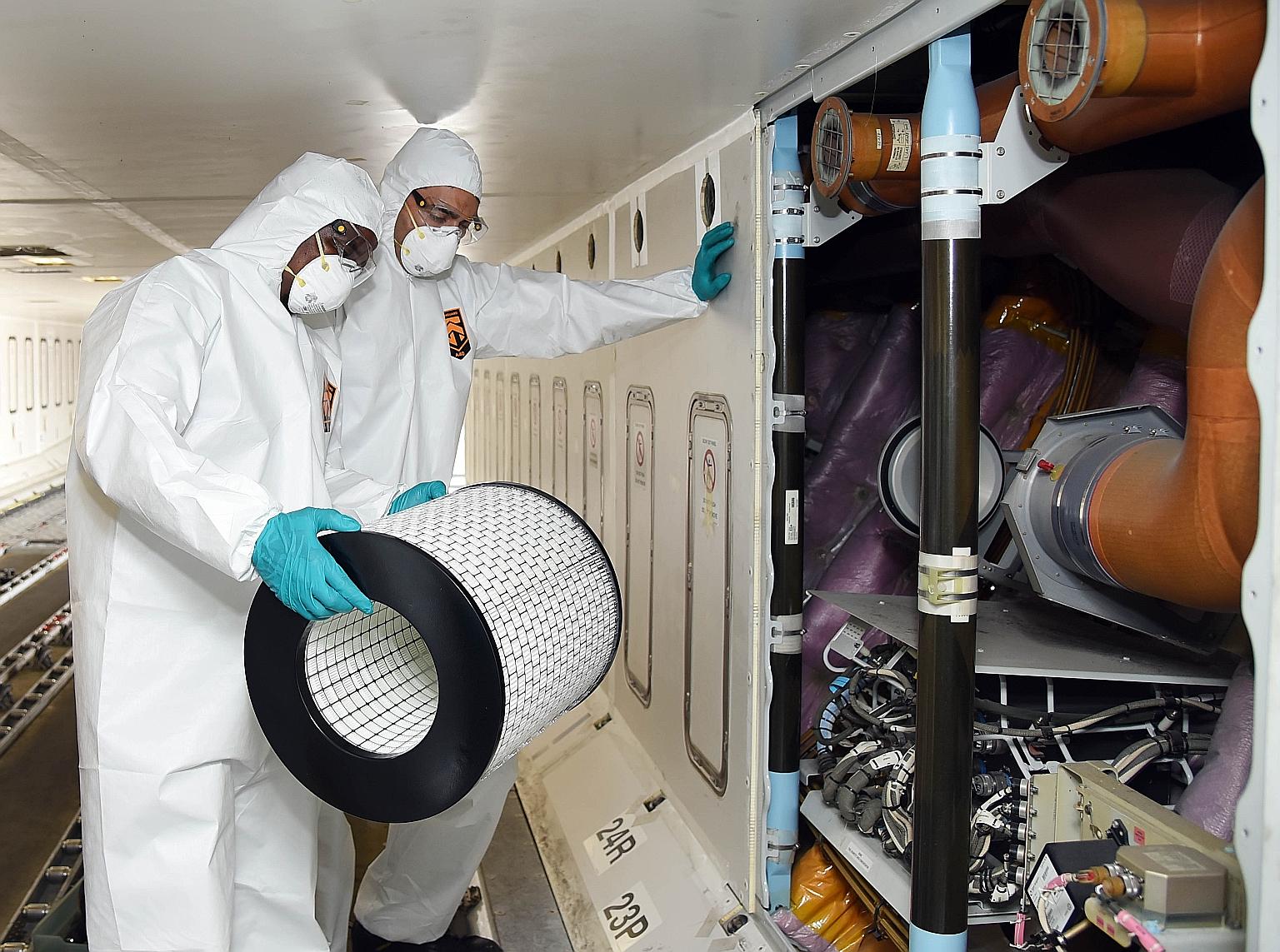 Cleaning staff changing air filters on board an Emirates aircraft in Dubai as part of sterilisation efforts against the coronavirus. The aviation industry is among sectors hard hit by the virus outbreak. PHOTO: AGENCE FRANCE-PRESSE