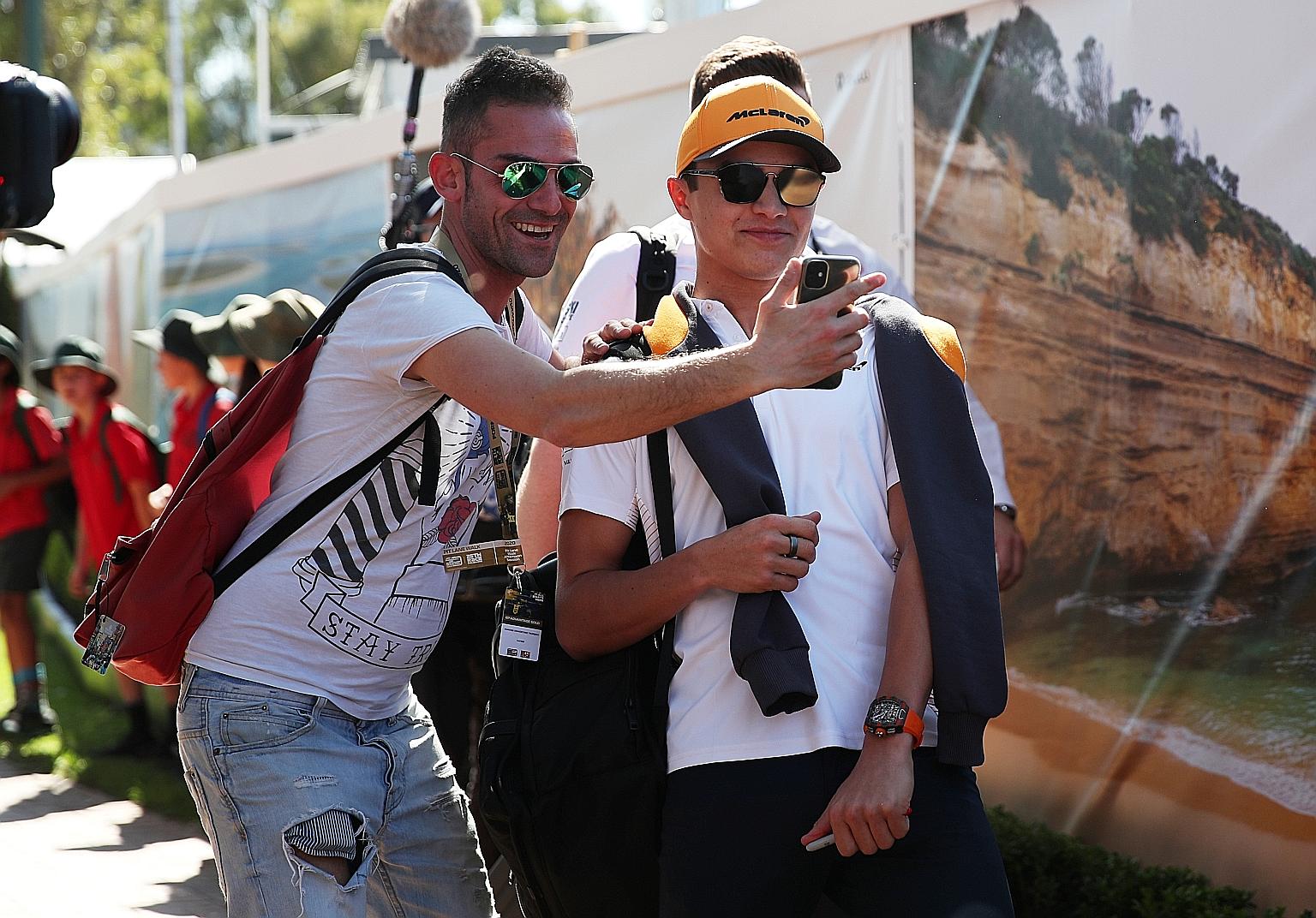 McLaren's Lando Norris taking a wefie with a fan at Albert Park in Melbourne yesterday. The team later withdrew from the opening race. PHOTO: REUTERS