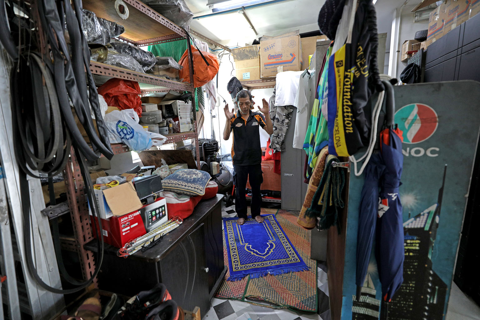Mr Azman Haji Saat, 54, owner of Man Garage, praying in his car workshop at Autobay@Kaki Bukit yesterday. He usually goes to Masjid Alkaff Kampung Melayu for Friday prayers, but the mosque was closed.