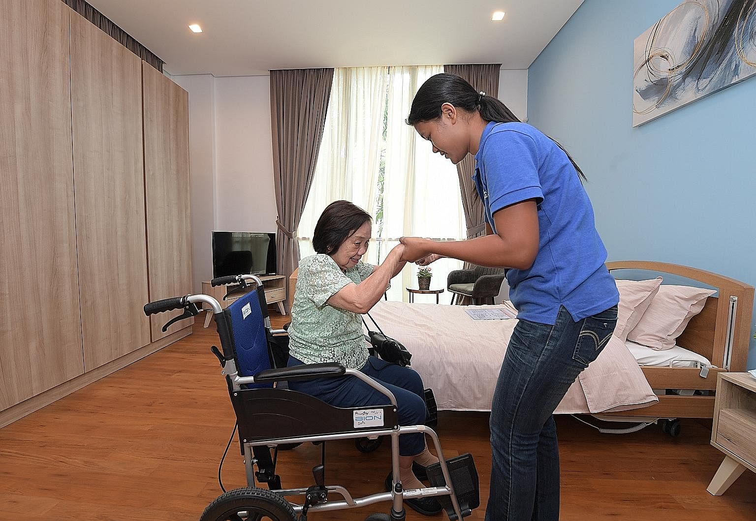Above: Ms Alice Soh, with caregiver Thae War Soe, 31, visiting St Bernadette's Sembawang facility yesterday. She is a resident at the group's Adam Road facility. Left: The Sembawang facility's metal-and-glass construction makes the four-storey, 5,000