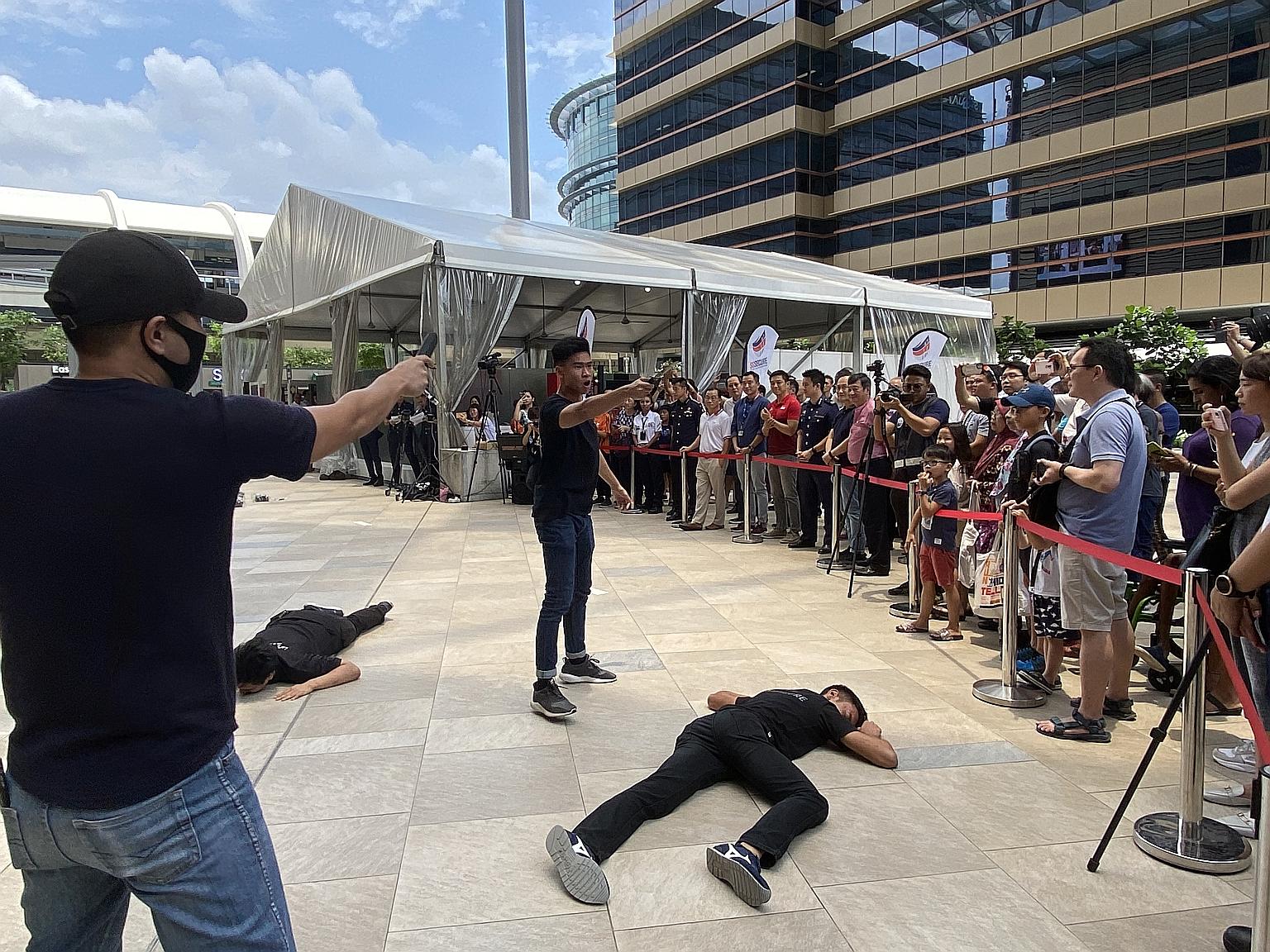 Speaker of Parliament Tan Chuan-Jin (in red), along with other MPs in the area, viewing an exercise demonstration at an SGSecure roadshow outside the Paya Lebar Quarter mall yesterday.