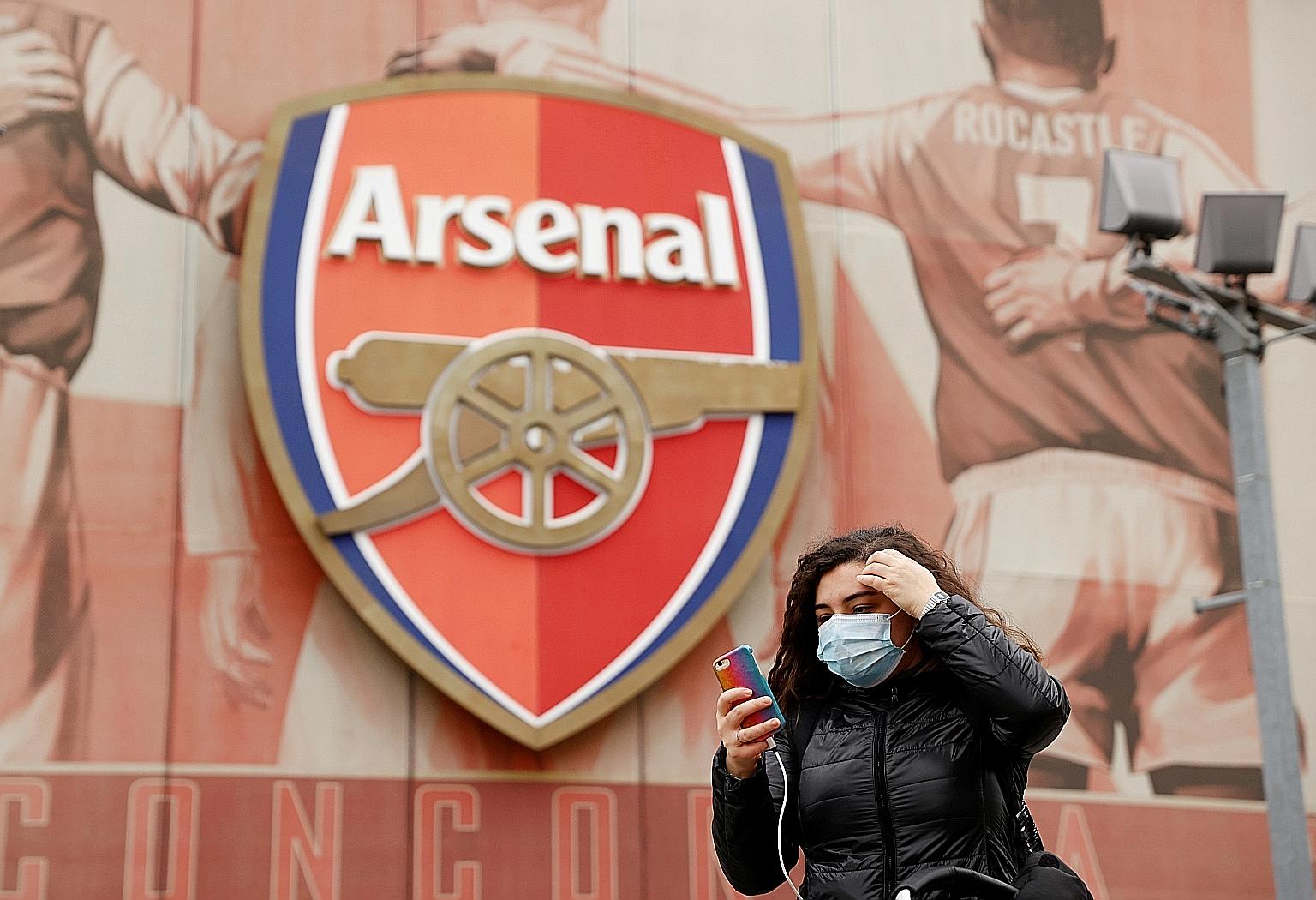 A woman wearing a mask walking past the Emirates Stadium in London. Arsenal manager Mikel Arteta's positive test for the coronavirus was the spark that led to the EPL's suspension. PHOTO: REUTERS