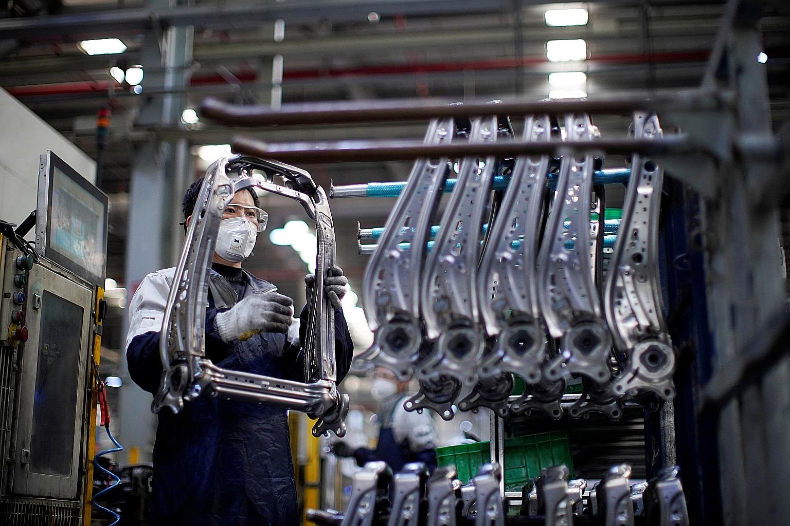 A masked employee at a car factory in Shanghai in February - before the Chinese authorities virtually shut down the world's second-largest economy to stop the coronavirus outbreak. Now, factories are re-opening but face new problems. Tens of millions