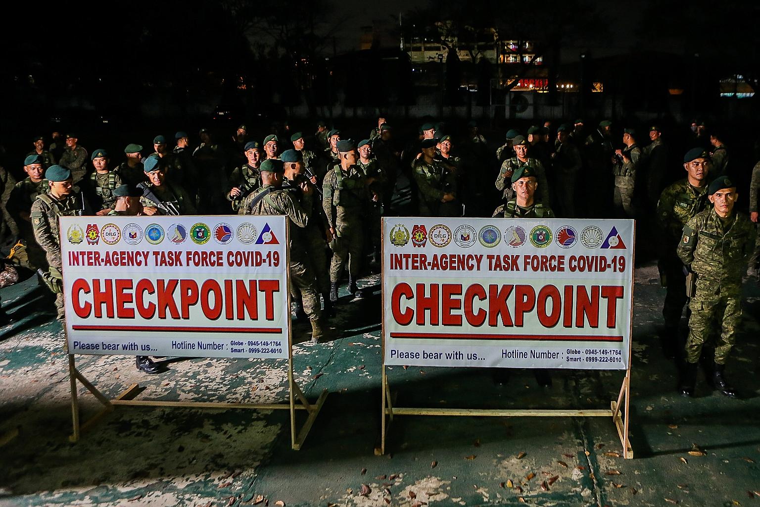 Philippine soldiers awaiting deployment at checkpoints yesterday in Valenzuela, south of Manila, as Metro Manila began a month-long lockdown amid a growing number of local Covid-19 cases.