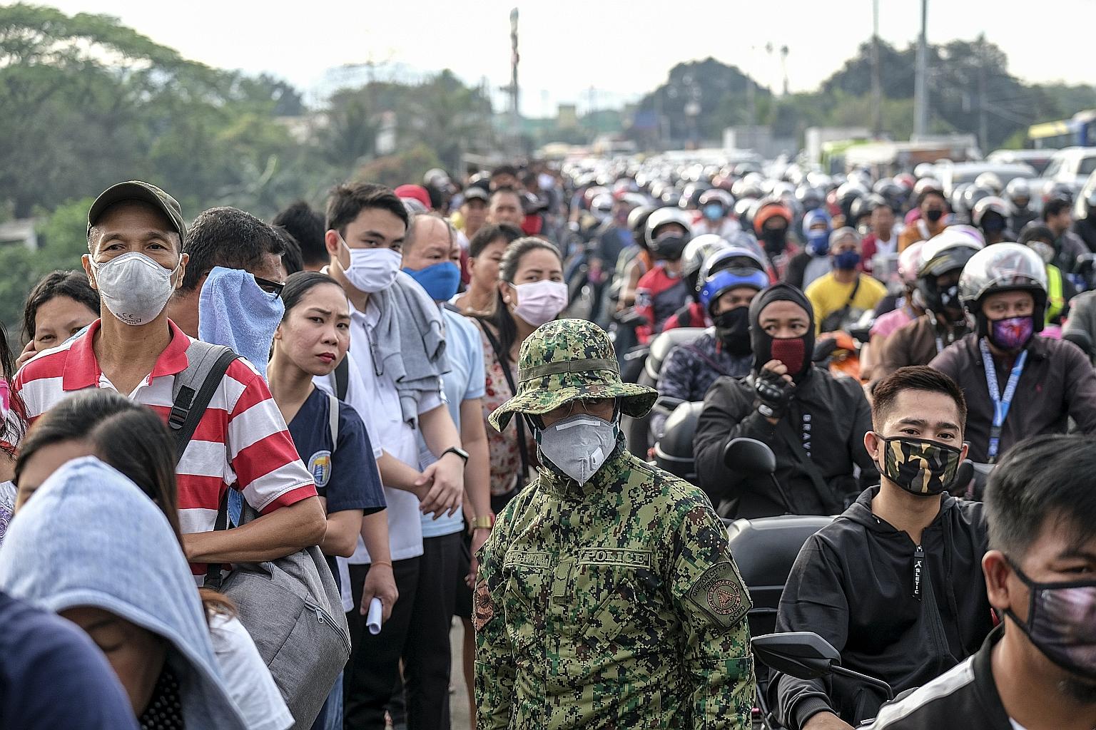 A member of the Philippine Army standing guard as commuters and motorists travelling into Metro Manila waited in line to pass through a checkpoint in Quezon City yesterday. PHOTO: BLOOMBERG