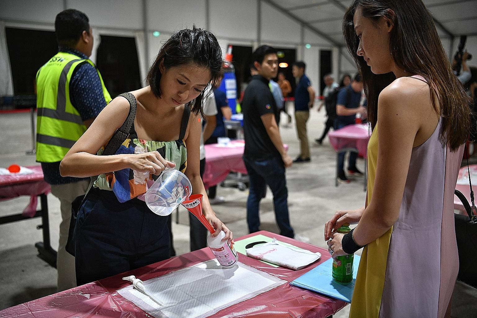 Volunteer Agnes Poon, 35, pouring hand sanitiser into a bottle at Pasir Ris Elias Community Club yesterday. All households in Singapore will get 500ml of the hand rub free of charge in a Temasek Foundation initiative, starting next Monday. Distributi