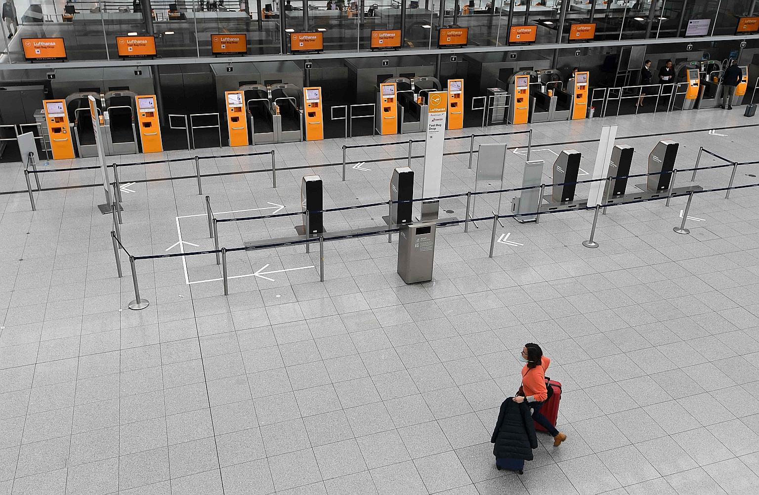 A woman wheeling her luggage through an empty check-in hall in Franz Josef Strauss airport in Munich, southern Germany, on Tuesday. Many flights have been cancelled by airlines because of the coronavirus and restrictions on travel by governments acro