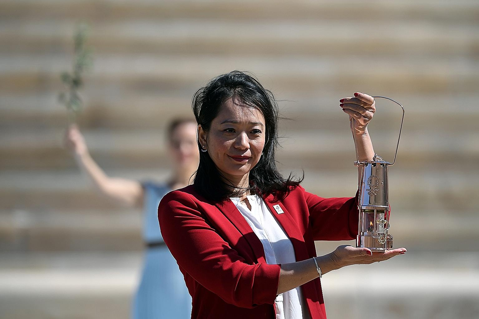 Former Japanese swimmer Naoko Imoto with the Olympic flame during a closed-door handover ceremony in Athens' Panathenaic stadium, site of the first modern Olympics in 1896. The flame will arrive in Japan today for the start of the domestic relay for 