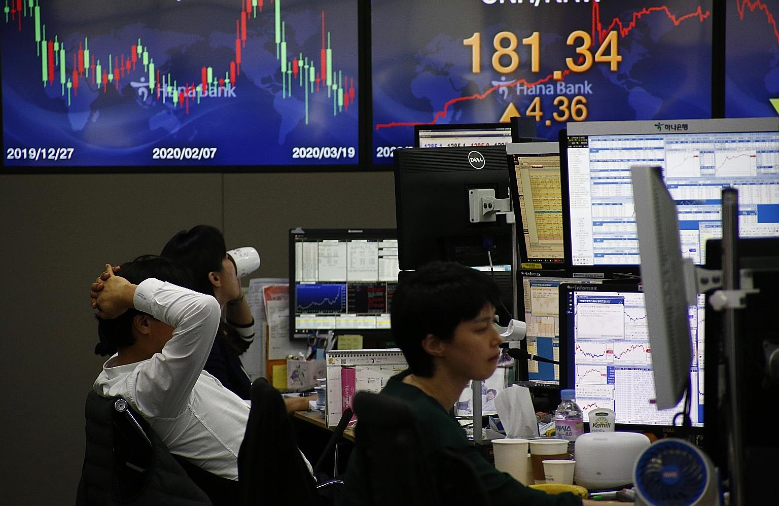 Dealers at Hana Bank in Seoul, South Korea, yesterday. The benchmark South Korea Composite Index plunged 8.4 per cent, leading the sell-off in Asian markets.
