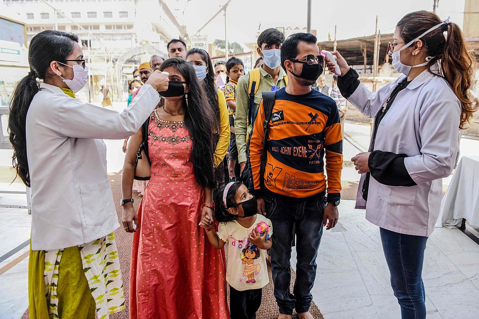 Health workers checking the temperature of devotees at the entrance of the Durgiana Temple in Amritsar in the northern Indian state of Punjab on Wednesday. The state, which saw India's fourth coronavirus fatality yesterday, has suspended public trans