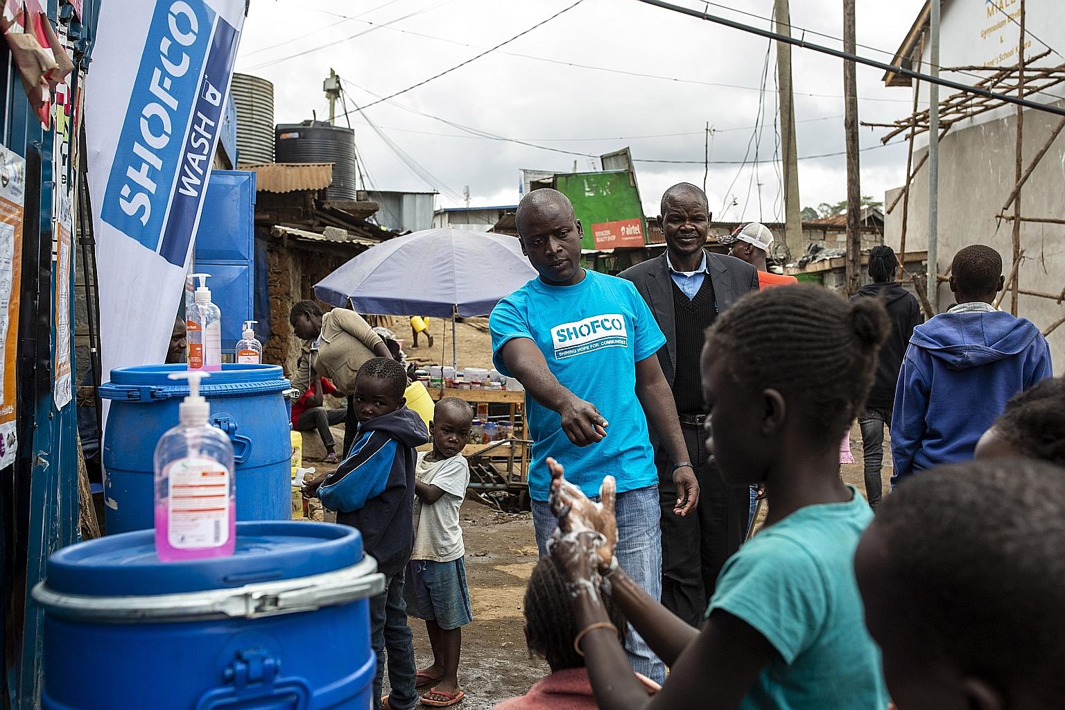 Volunteers assisting children yesterday at a temporary hand-washing station set up by non-profit Shining Hope for Communities in the Kenyan capital Nairobi. UN chief Antonio Guterres has appealed to G-20 nations to help African countries and others i
