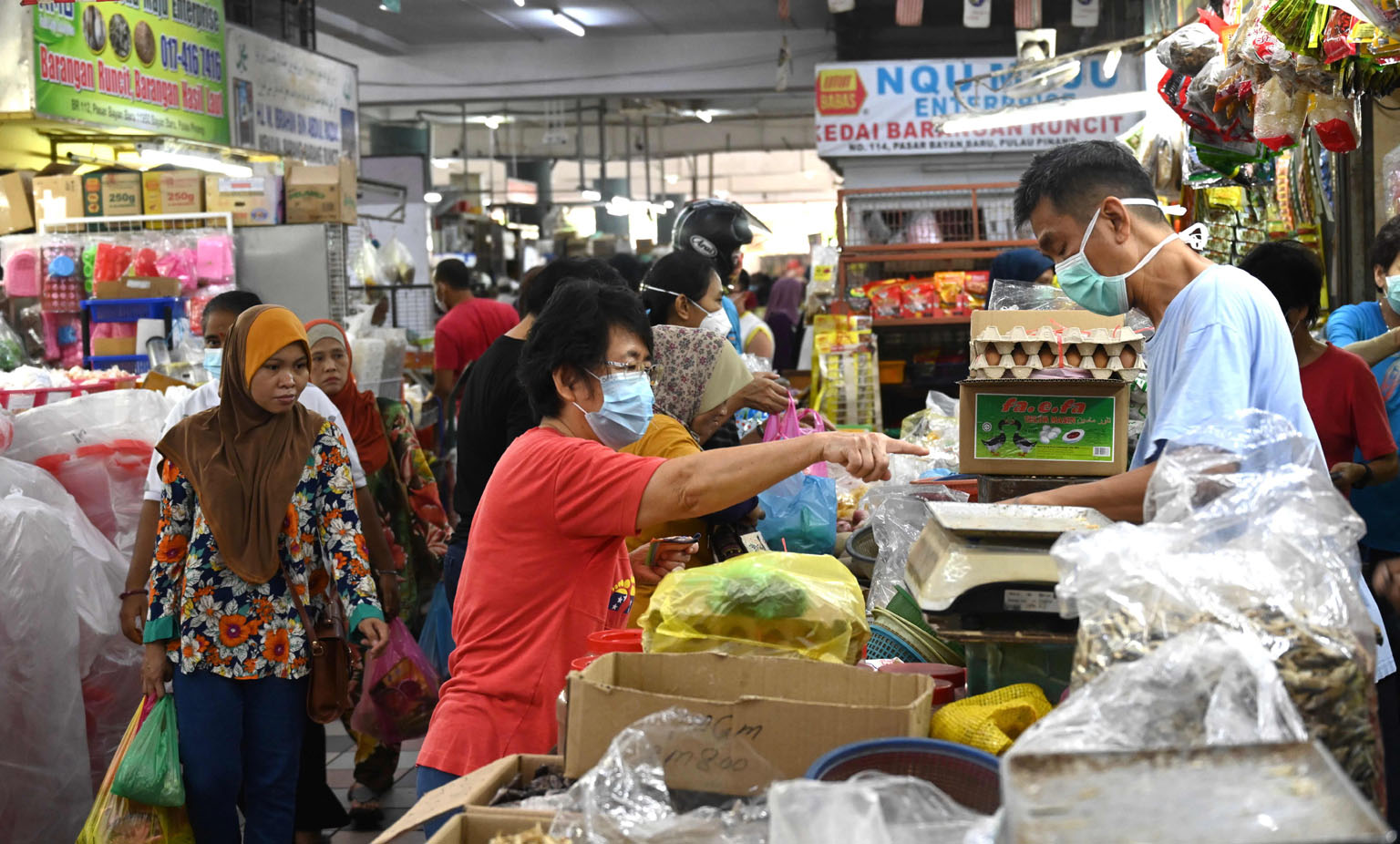 Shoppers buying fresh produce at a market in Penang on the third day of a partial lockdown in Malaysia yesterday. Except for essential services such as supermarkets, banks, petrol stations and pharmacies which will remain open, schools, offices, park
